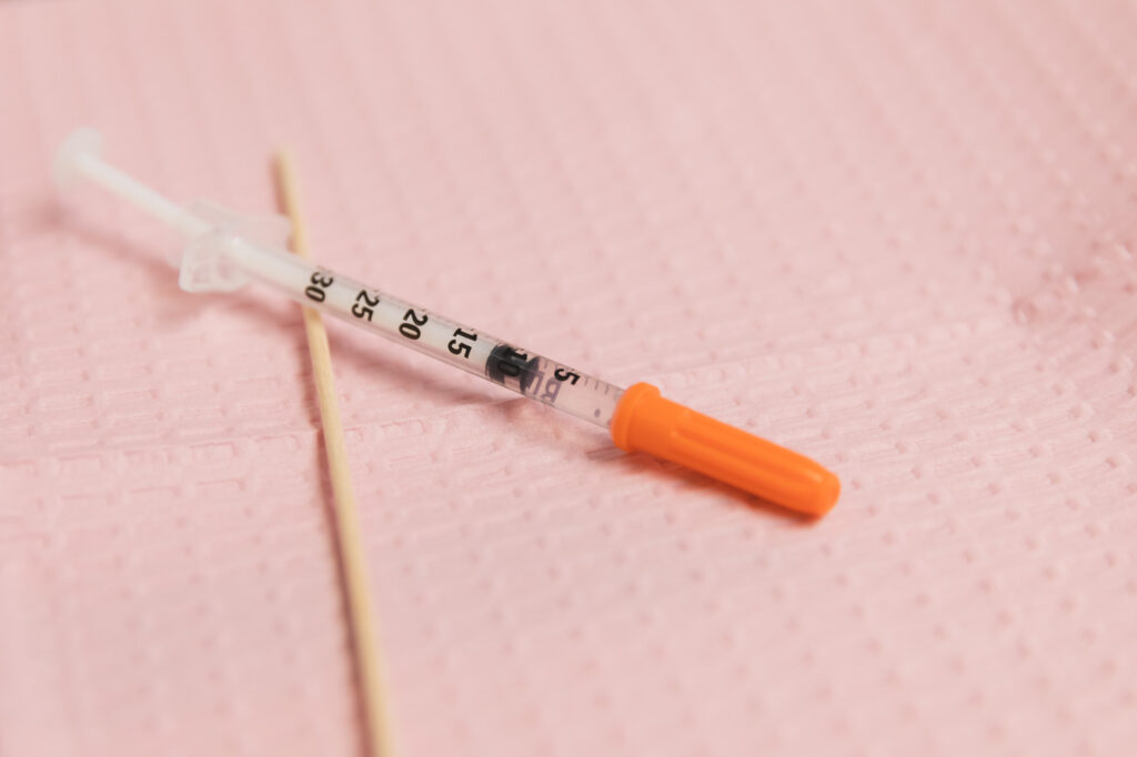 Pink background with syringe for botox near Brentwood, TN