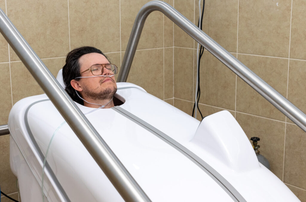 A male patient relaxes in the HOCATT sauna chamber for joint pain relief near Nashville