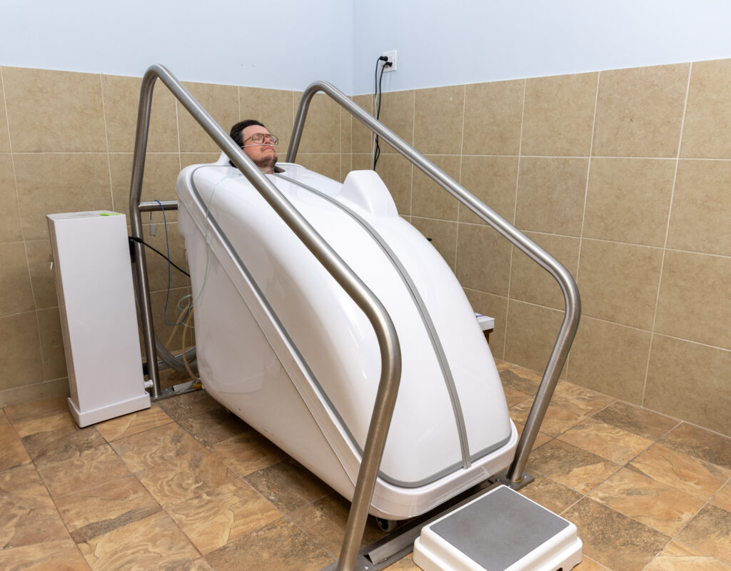 A male patient relaxes with his eyes closed in am infrared sauna in Hendersonville, TN