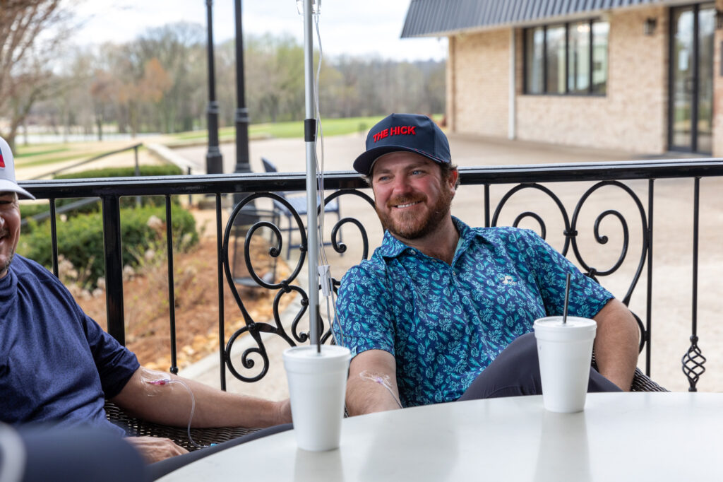 A man smiles while receiving an infusion with friends to stay hydrated in Nashville