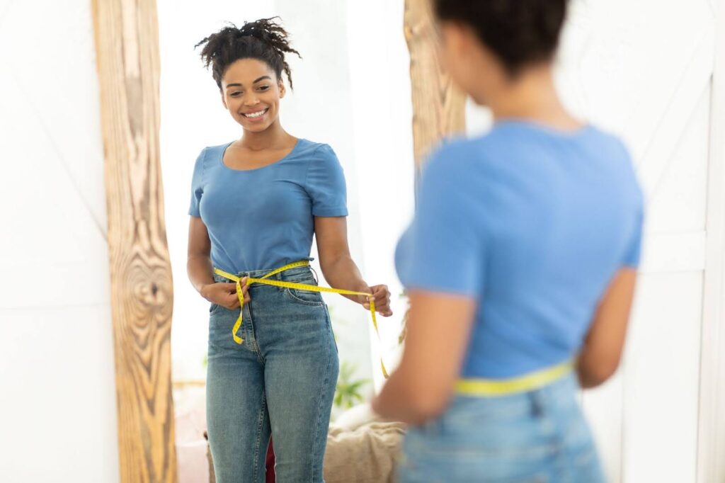 A woman mearues her waist in front of a mirror after receiving semaglutide near Mt. Juliet, TN.