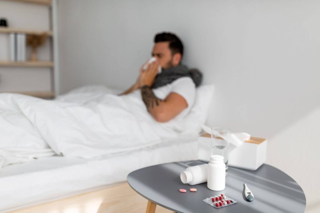 A man blows his nose while sick in bed before receiving an immune system booster in Franklin, TN