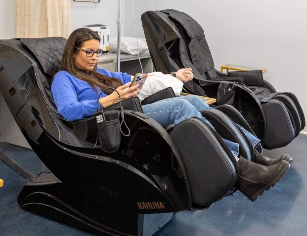 A young woman sits in a very comfortable, custom treatment chair at Intravenous Solutions, receiving her IV hydration. She can also choose to do it at home, or where she wishes, with our mobile IV therapy near Brentwood, TN.