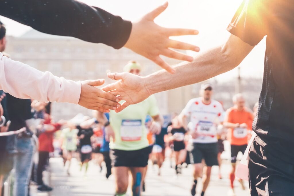 Child's hand giving highfive to a runner at a marathone in Nashville. The runner will seek IV therapy for their athletic recovery in Nashville.